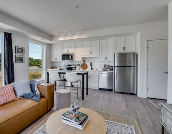 a living room with a couch and a table with a kitchen in the background
